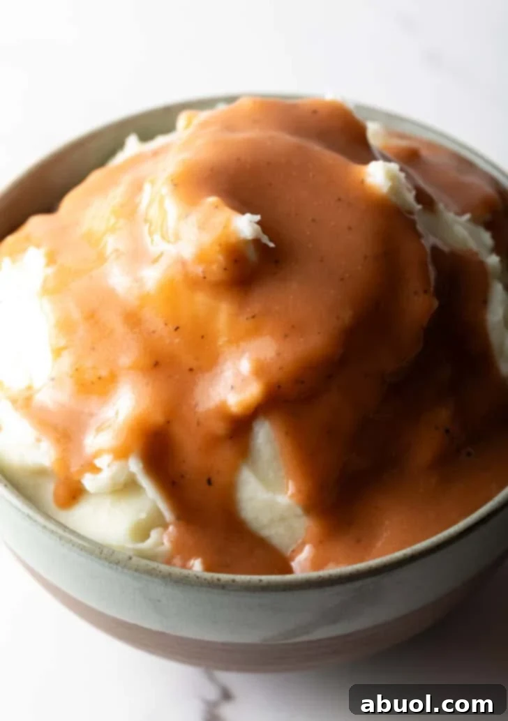 A beautifully presented bowl of mashed potatoes with homemade gravy poured generously on top, ready to be served.