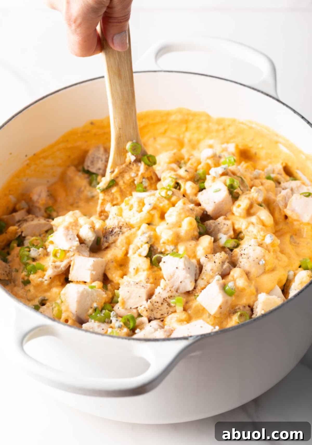 Stirring chicken into buffalo chicken mac and cheese.