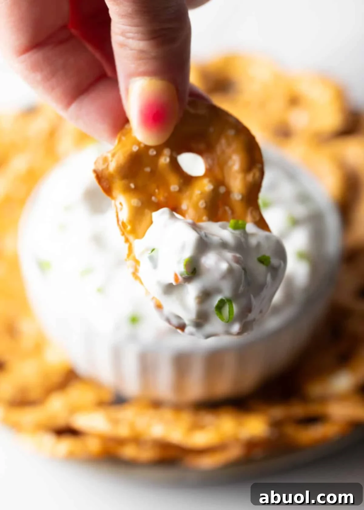 Hand holding a pretzel with a scoop of olive dip to camera.