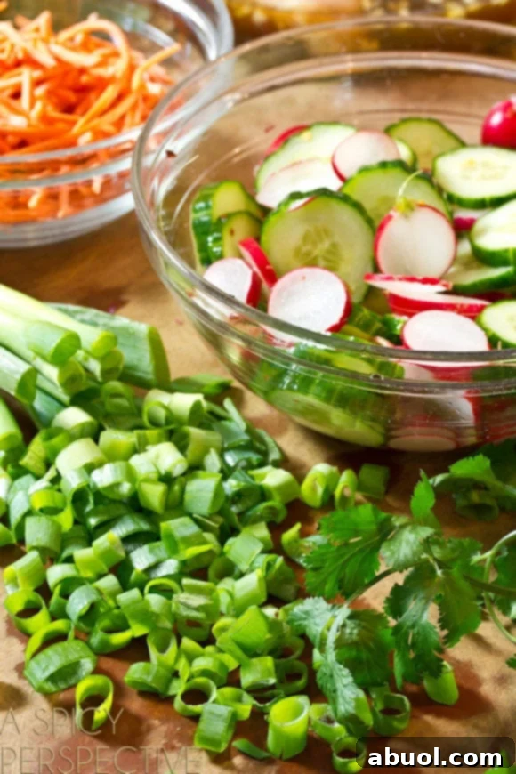 Prepped ingredients: Sliced green onions, and a glass bowl of sliced cucumbers and radishes soaking in pickling liquid.