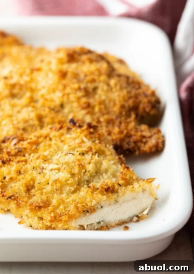 A single baked chicken cutlet on a white plate, beautifully sliced to reveal its tender, juicy interior, ready to be enjoyed.
