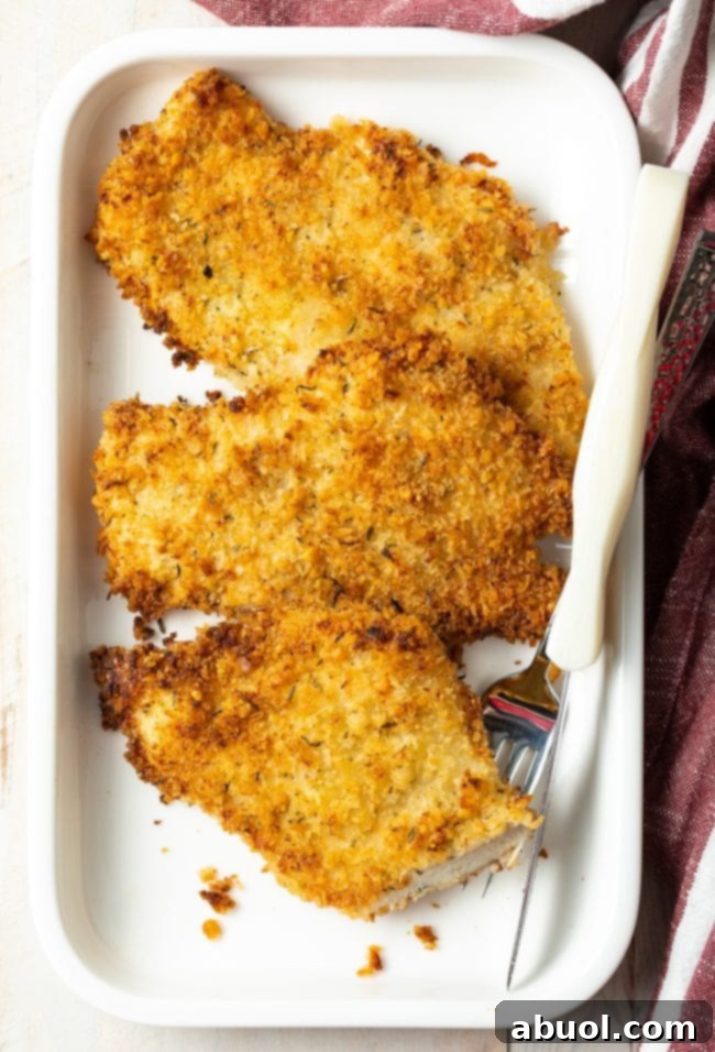 A beautifully plated cooked chicken cutlet with a fork, showing a perfect bite taken out, highlighting the tender, juicy interior and crispy crust.