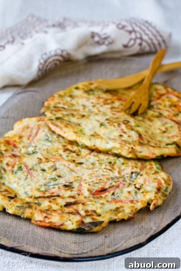 Korean Jeon: Savory Delights 7 Two perfectly fried Korean pancakes, golden and inviting, resting on a plate just after being removed from the skillet, highlighting their ideal cooked state.