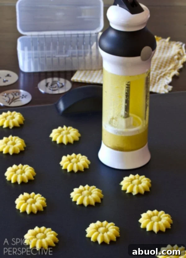 Close-up of golden yellow Lemon Pressed Cookies shaped like flowers, demonstrating the versatility of a cookie press gun.