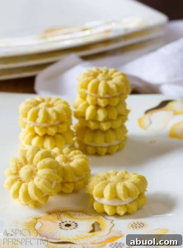 Stacked Lemon Spritz Cookies with creamy lemon filling on a white plate, showcasing their delightful sandwich form.