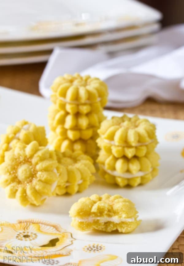 Unfilled Lemon Spritz Cookies and lemon cream filling in a piping bag, ready to be assembled into sandwich cookies.