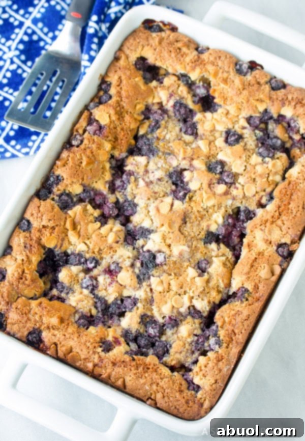 Baking pan full of uncut Blueberry White Chocolate Blondies with spatula in the background.
