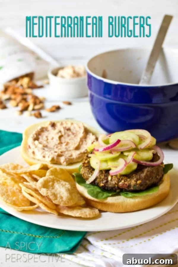 A delicious Mediterranean burger, loaded with fresh toppings, served on a plate with crispy chips on the side, showcasing its vibrant colors and inviting texture.