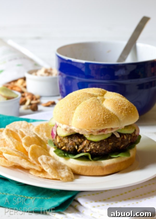 A beautifully composed Mediterranean burger, highlighting its fresh cucumber slaw and creamy aioli, served alongside a savory side. This image is perfect for sharing on social media with hashtags like #burgers #hamburgers #summer.