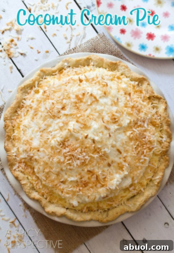 A perfectly baked whole Coconut Cream Pie, an overhead shot showcasing its beautiful golden-brown coconut crust and smooth, inviting surface, ready to be sliced.