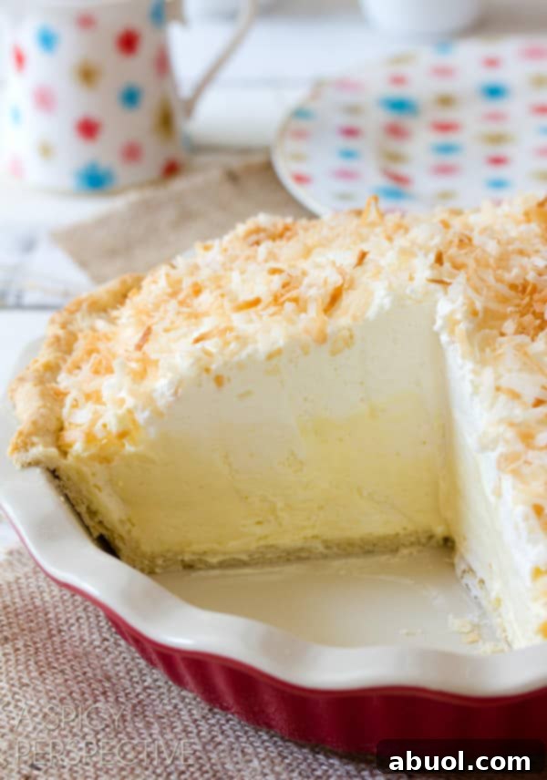 A tantalizing view of a Coconut Cream Pie, with a slice already cut out, revealing the generous layers of thick, creamy filling and the distinct coconut crust.