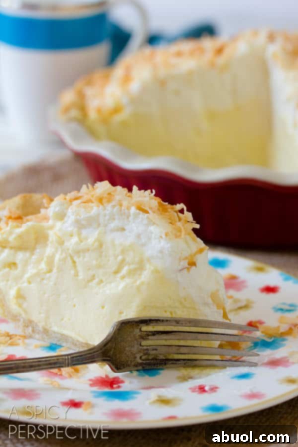 A close-up shot of a slice of Coconut Cream Pie, with a fork cutting through its thick, inviting layers of creamy filling and tender crust, garnished with toasted coconut.