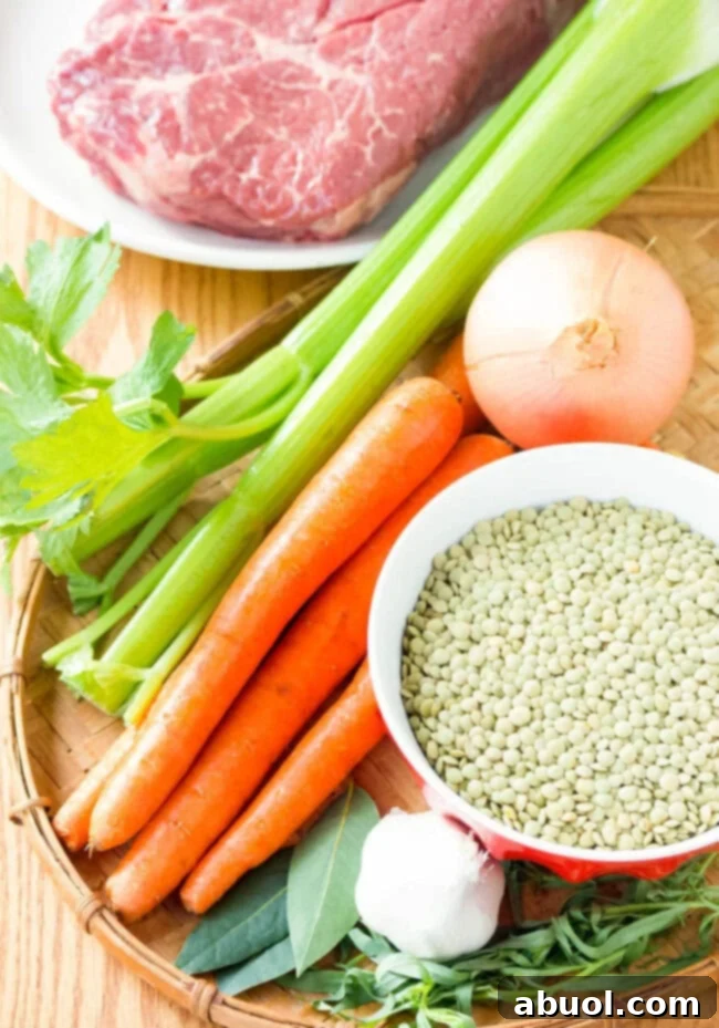 All the fresh ingredients needed for a hearty beef and lentil stew displayed on a cutting board.