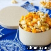 A mixed bowl of caramel and cheese popcorn, with bags of popcorn in the background, illustrating the delicious Chicago Mix.