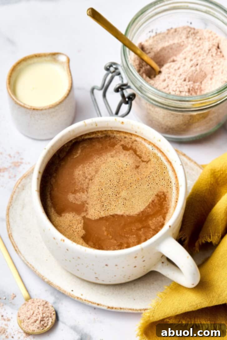 Mexican Mocha in a festive mug, with whole spices like cinnamon sticks and star anise around it