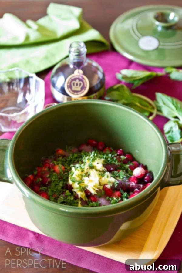 Fresh cranberries, raspberries, ginger, mint, sugar, and raspberry liqueur gathered in a small saucepot, ready to be cooked into a delicious sauce.