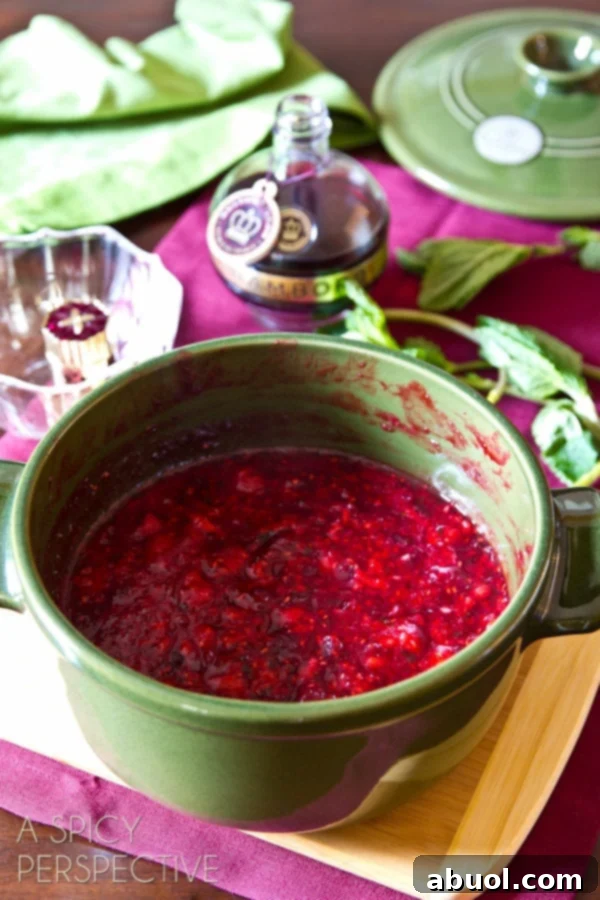 A close-up of a bubbling pot of homemade cranberry raspberry sauce, showcasing its rich color and chunky texture as it finishes cooking.