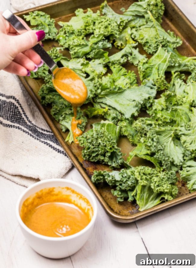 Hand pouring butter spice mixture over kale chips.