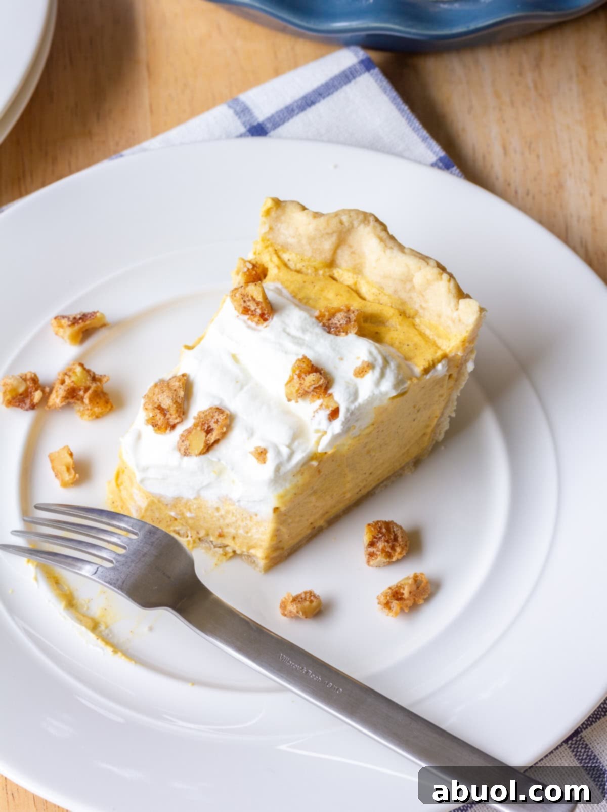 Dessert-Time A delectable slice of Fluffy Pumpkin Cream Pie, elegantly presented on a white plate, showcasing its creamy layers and perfect crust.