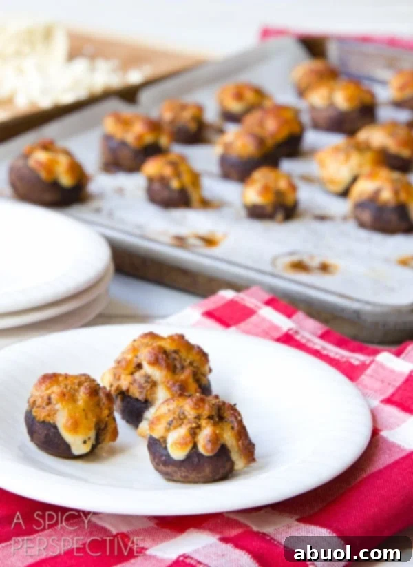 Baked Chorizo Stuffed Mushrooms served on a plate with more on a baking sheet in the background.