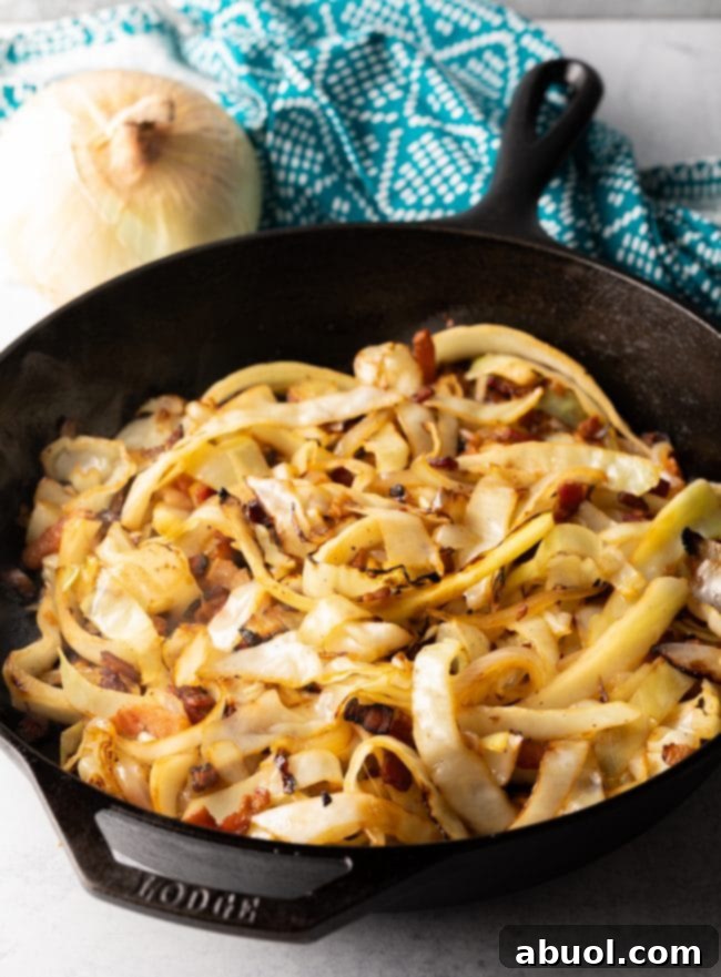 Tossing cooked noodles with sautéed cabbage and bacon