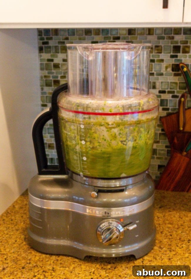 Zesty Salsa Verde Enchiladas 7 Roasted salsa verde ingredients being blended in a food processor.