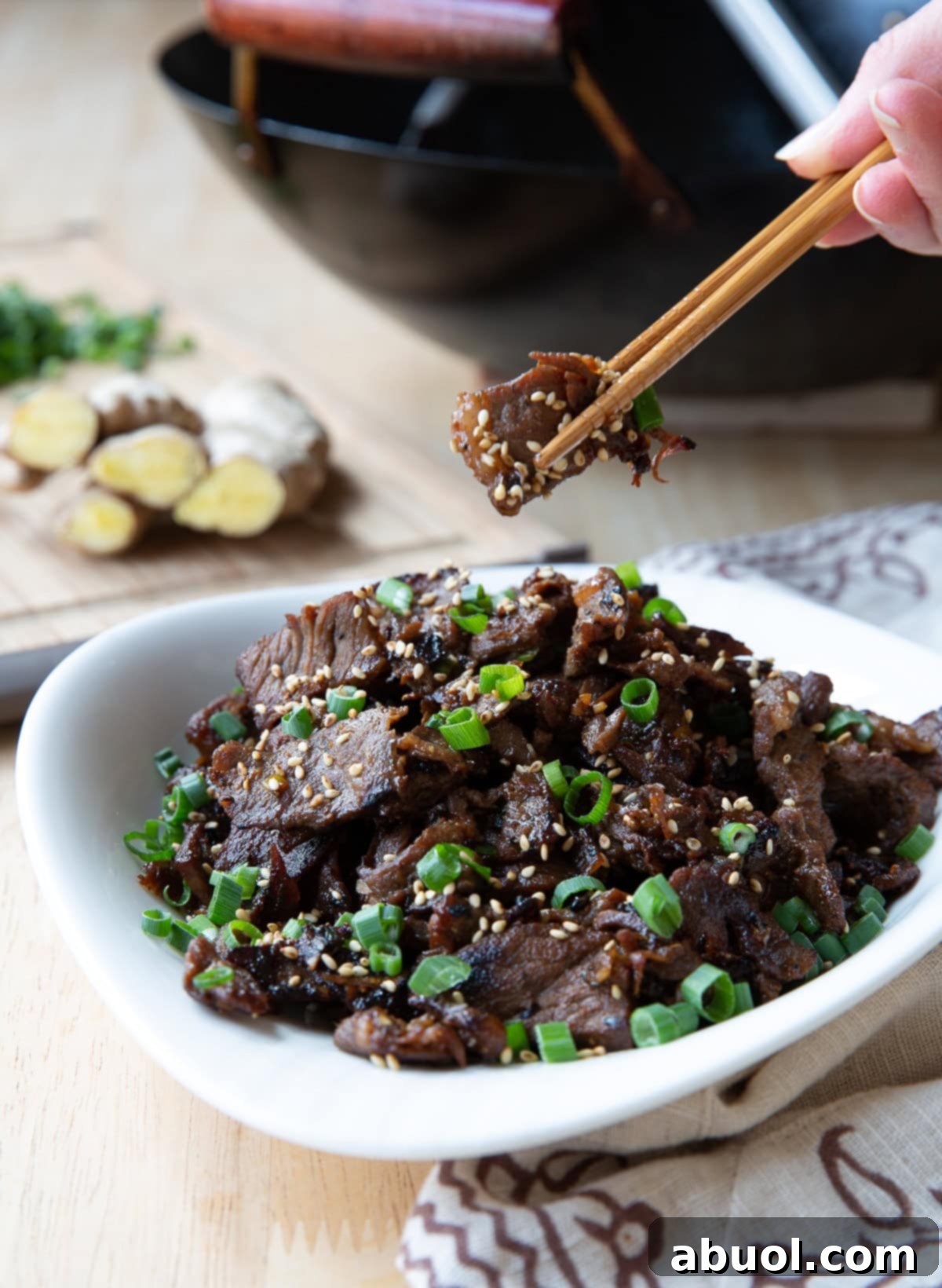 A pair of chopsticks gracefully picking up a succulent piece of beef bulgogi from a serving dish.