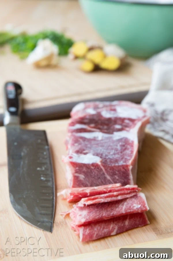 Hands expertly slicing frozen steak into thin pieces on a cutting board using a chef's knife.