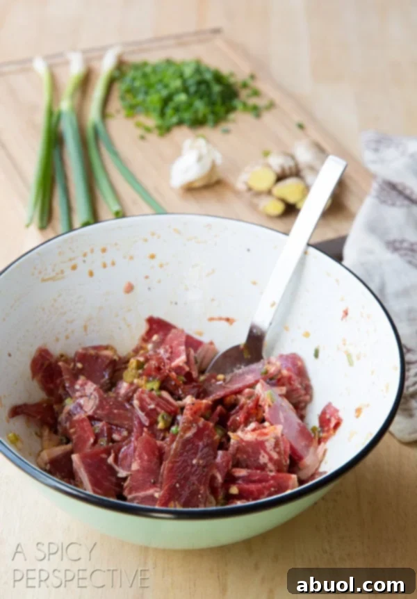 Thinly sliced beef marinating in a flavorful sauce within a white bowl, absorbing all the sweet and savory notes.