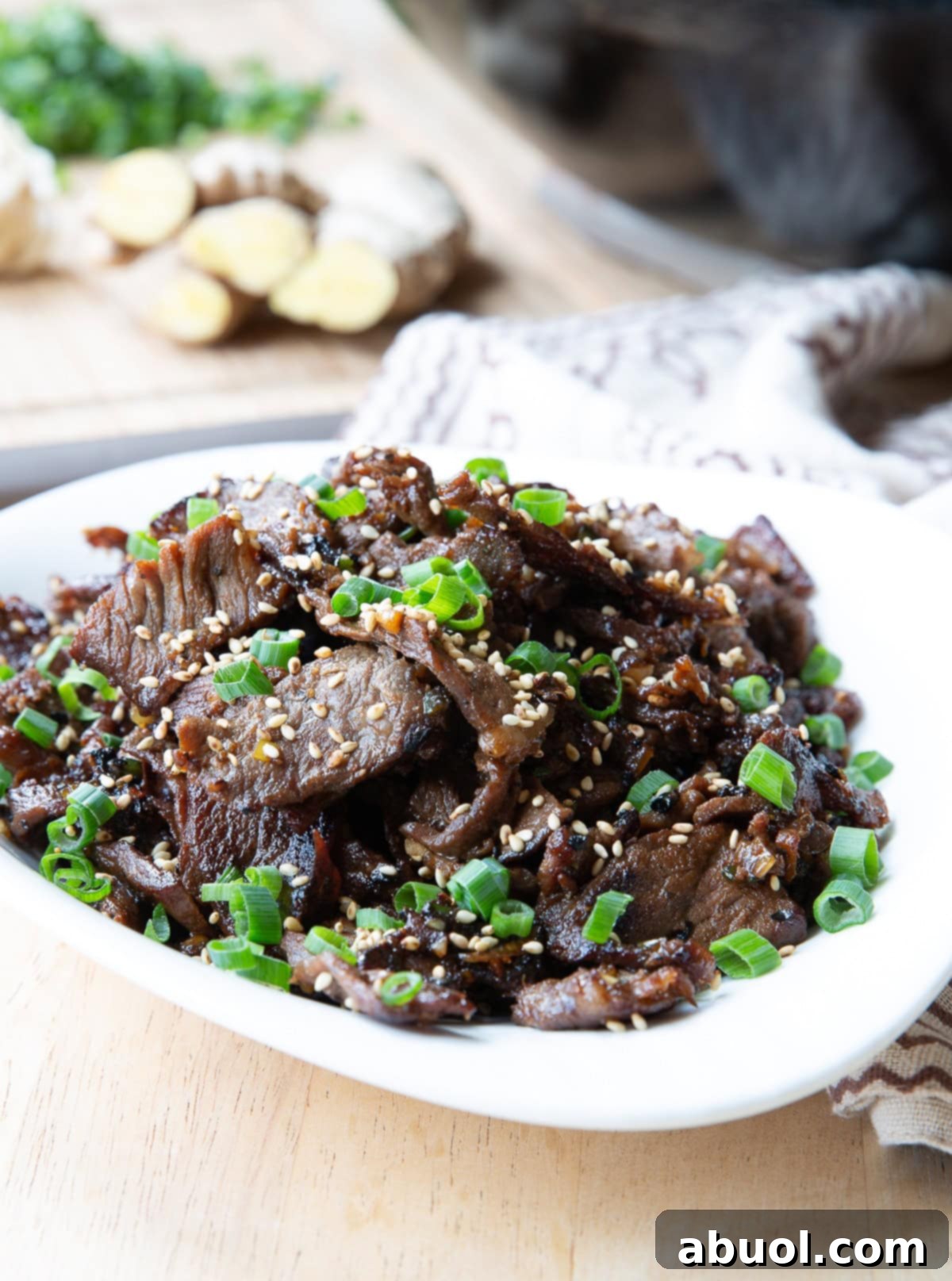 A large, beautifully arranged serving dish of bulgogi beef, garnished with vibrant sesame seeds and fresh scallions, ready for sharing.