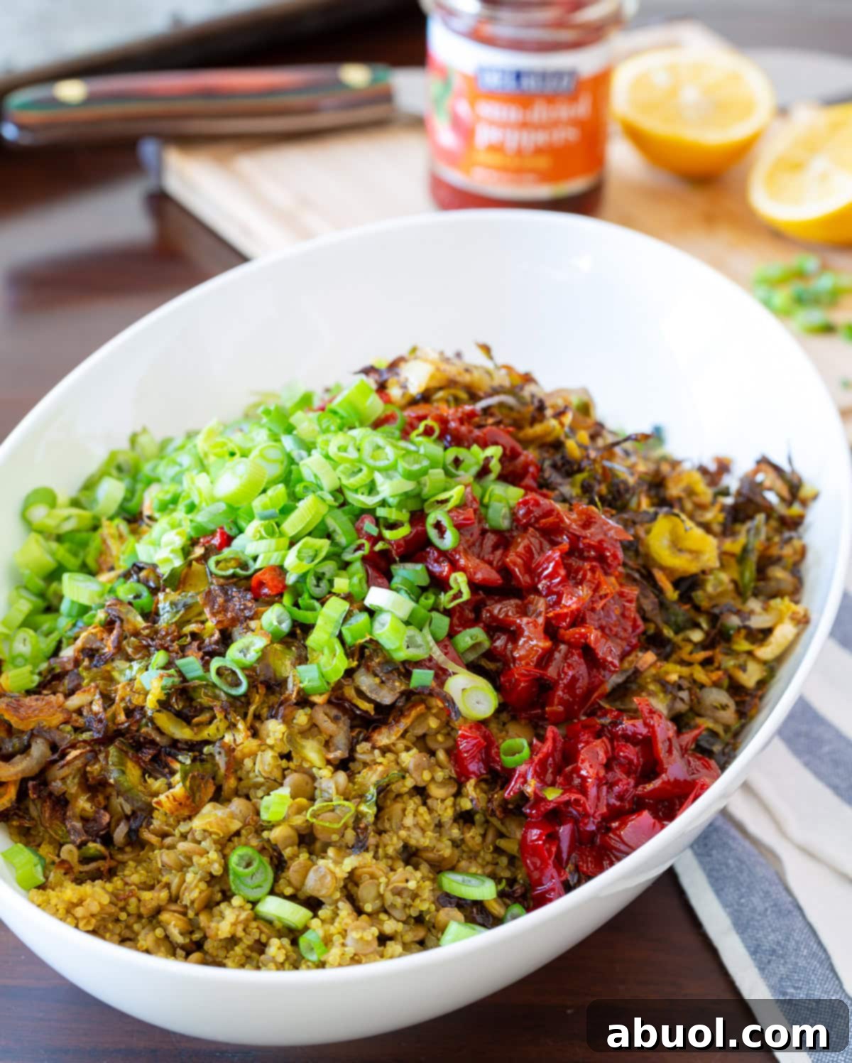 A large white bowl filled with Quinoa Lentil Salad, showcasing the mix of quinoa, lentils, peppers, onions, and Brussels sprouts.