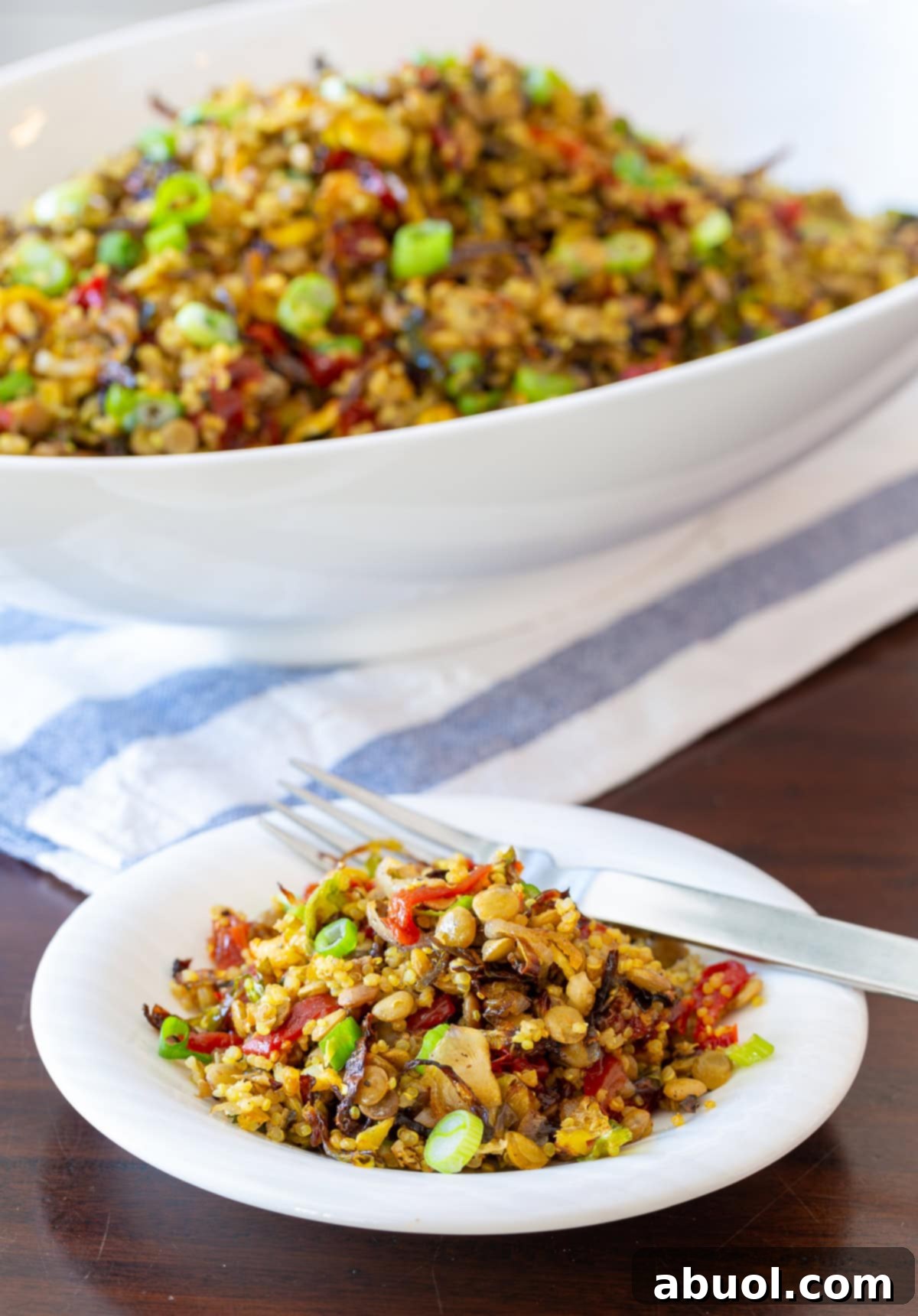 A side view of a white bowl filled with Quinoa Lentil Salad, with a fork holding a portion, suggesting a satisfying meal.