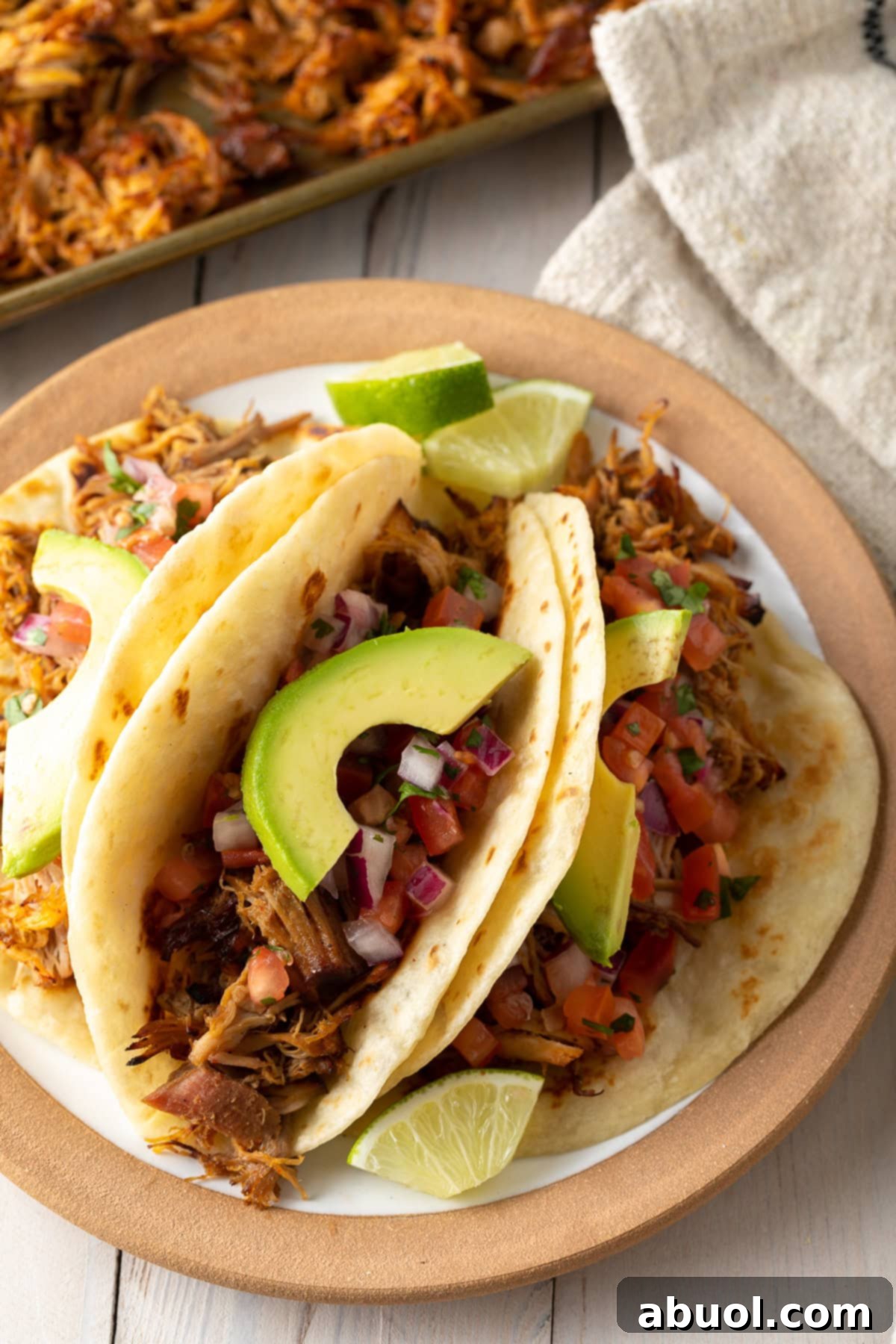 Carnitas tacos with fresh toppings on a rustic plate, showcasing crispy edges and vibrant colors.