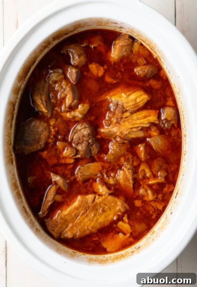 Pork carnitas that has been slow cooked for hours, appearing tender and juicy in the pot.