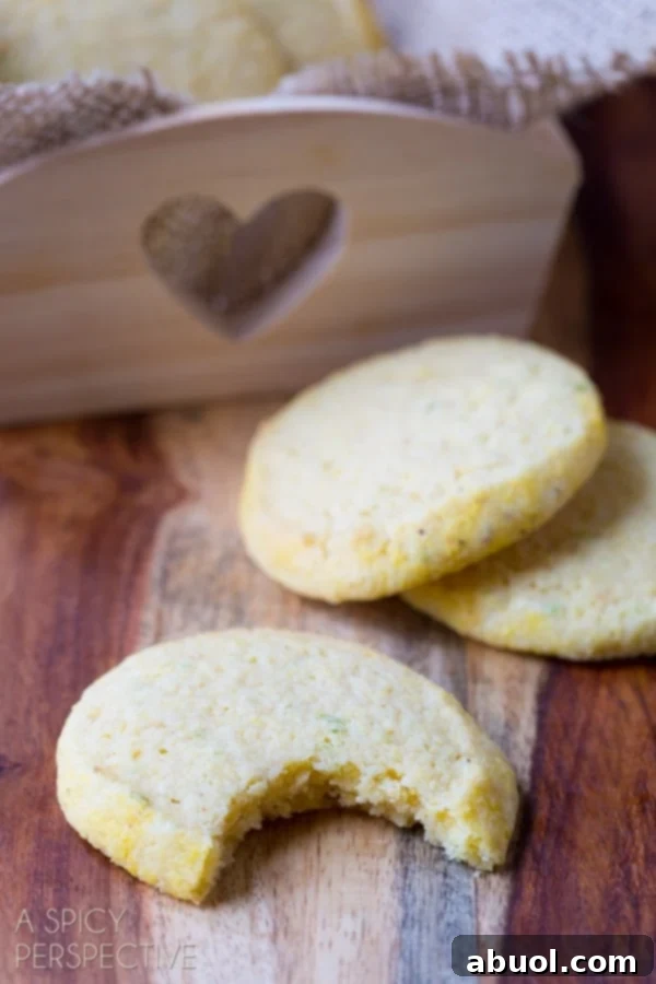 Tender Cornmeal Sugar Cookies, with one cookie having a small bite taken out, showcasing its perfect crumb.