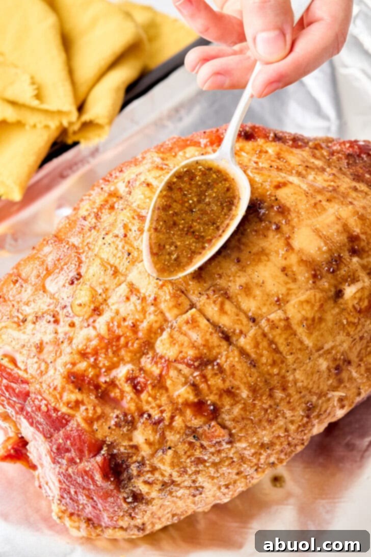 Step-by-step image: Applying the rich brown sugar glaze generously over the scored ham before baking.