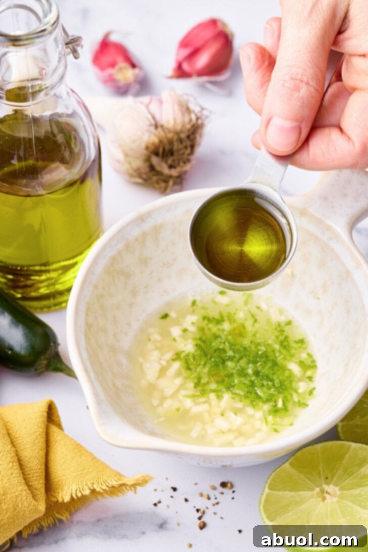 Mixing salmon marinade with olive oil being added to a small bowl. 