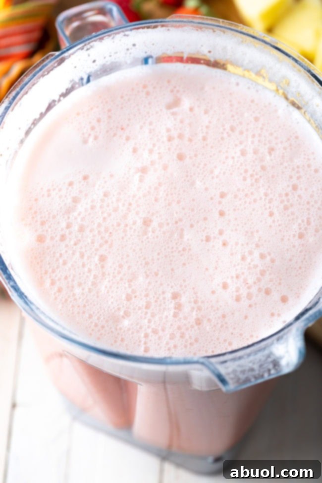Blended frothy pink agua fresca in a blender jar.