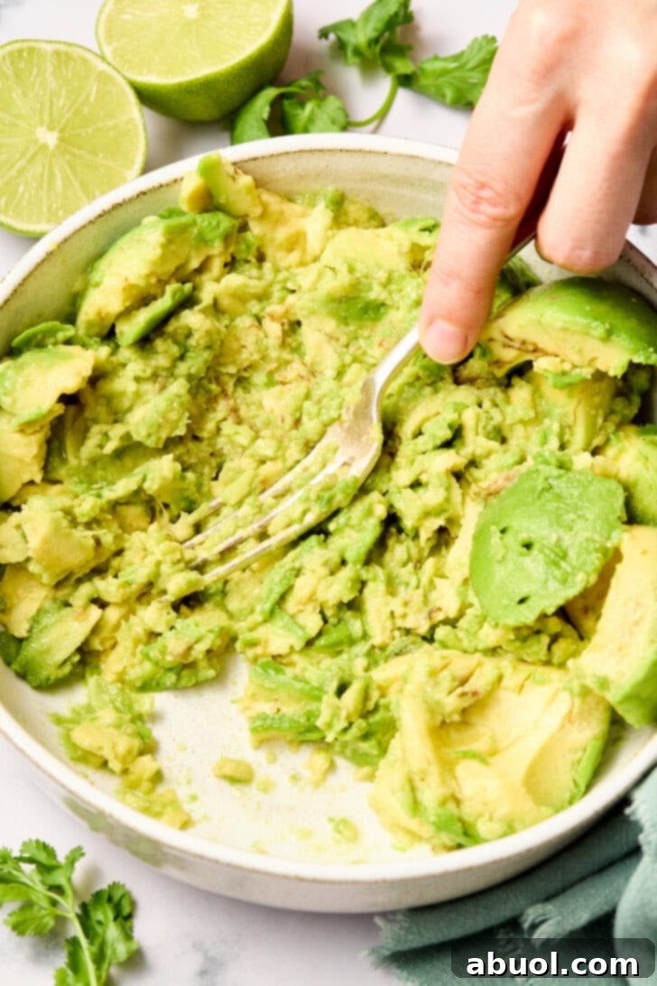 The Guacamole Gospel 6 A fork smashing the avocado in a bowl to achieve a creamy, chunky texture.