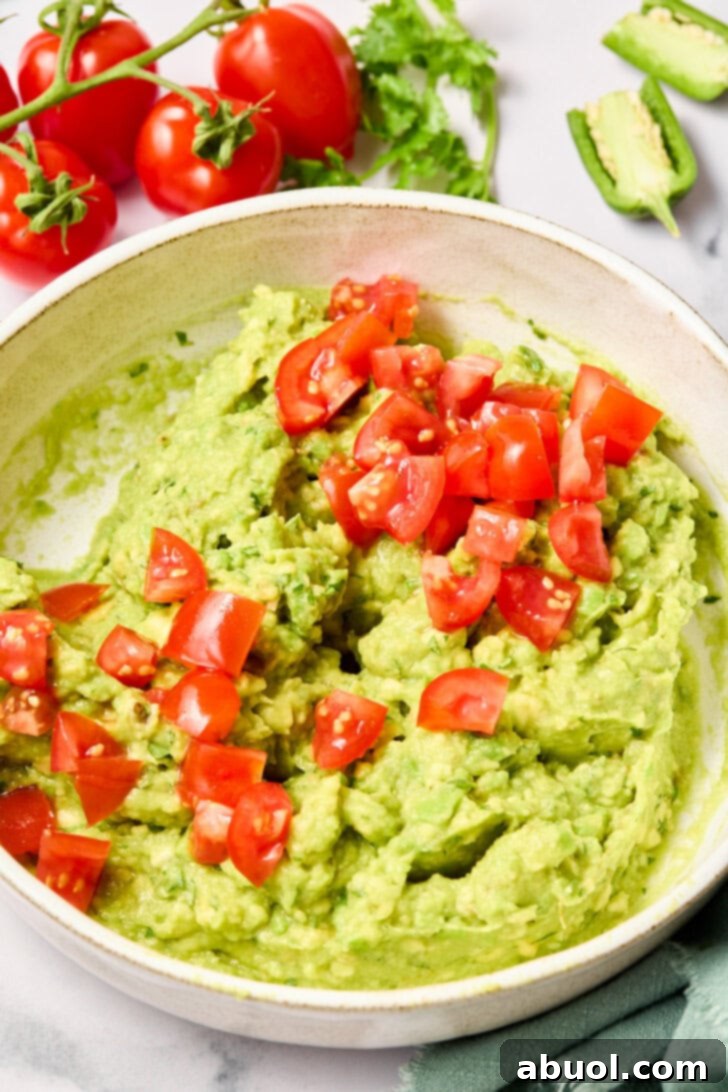 The Guacamole Gospel 8 Finely chopped tomatoes being mixed into the avocado mixture, adding color and freshness.