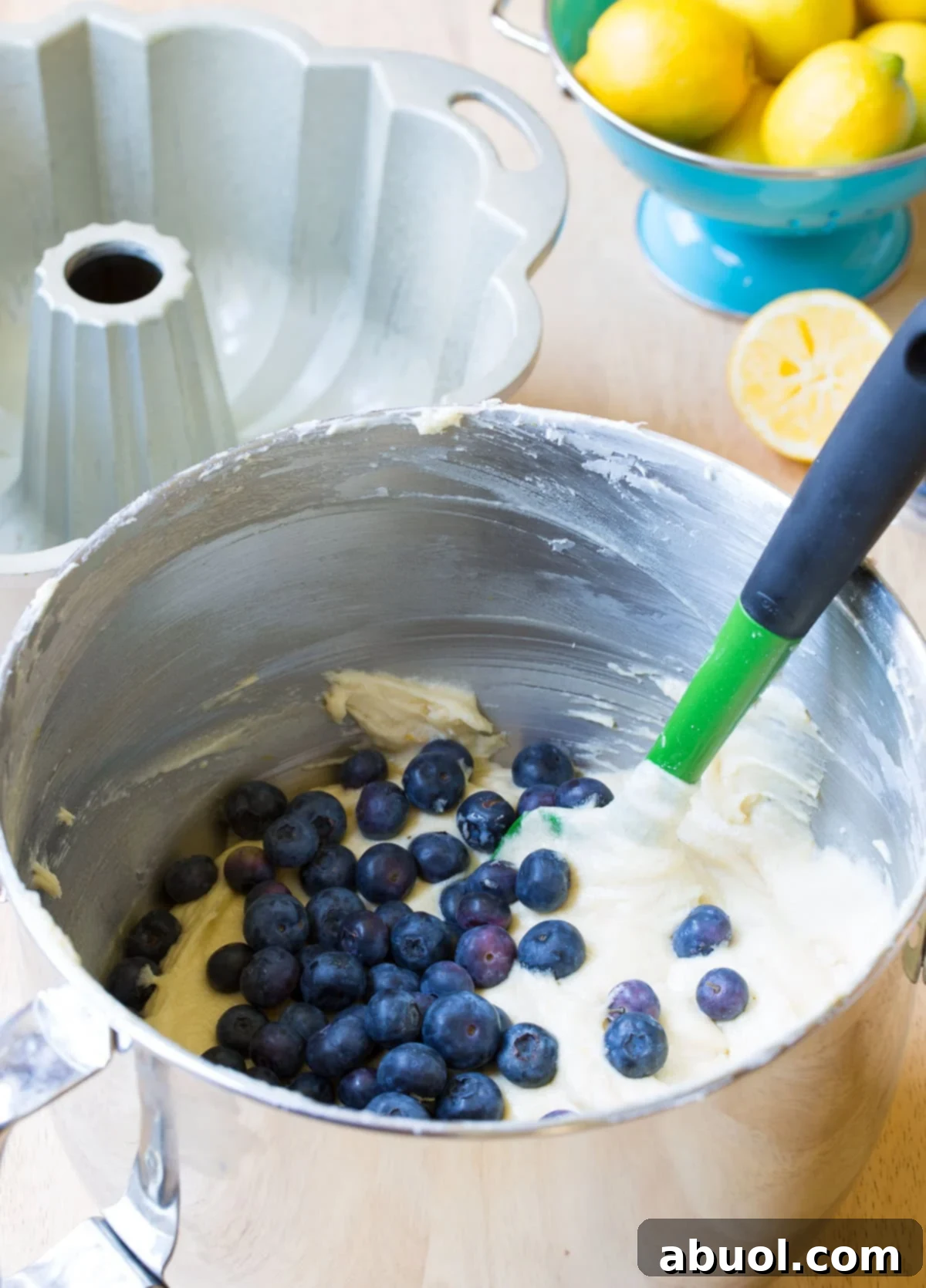 Cake batter in a mixing bowl with fresh blueberries being folded in.