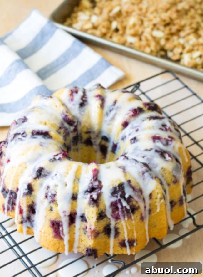 Buttermilk glaze being drizzled over a berry bundt cake on a cooling rack.