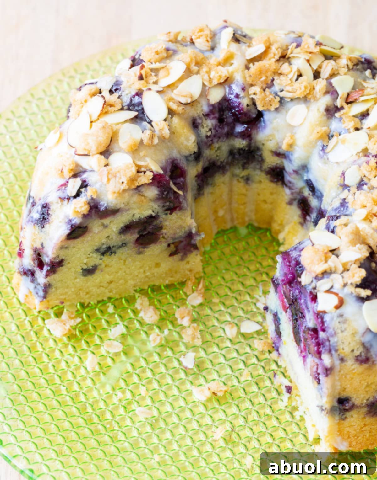 A blueberry muffin bundt cake with several slices already removed, showing the moist interior.