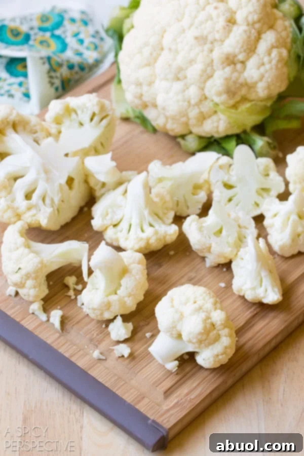 Fresh cauliflower florets on a cutting board, neatly chopped and ready for processing into rice.