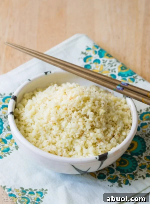 Low-Carb Roasted Cauliflower Rice in a decorative bowl with chopsticks, prepared for an Asian-inspired meal.