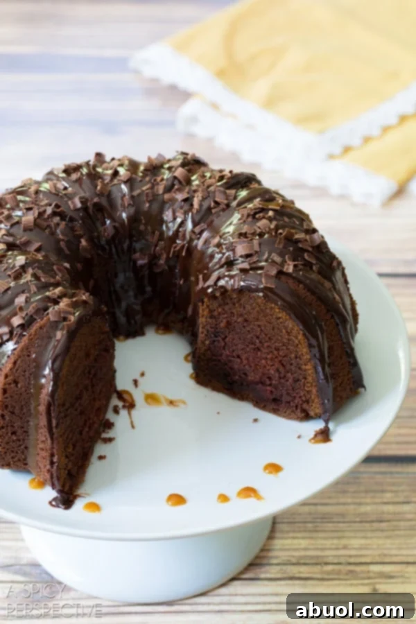 Boozy Baileys Bundt Bliss 4 A plated Baileys Irish Cream Bundt Cake with a large slice removed, showcasing its moist interior and luscious toppings.