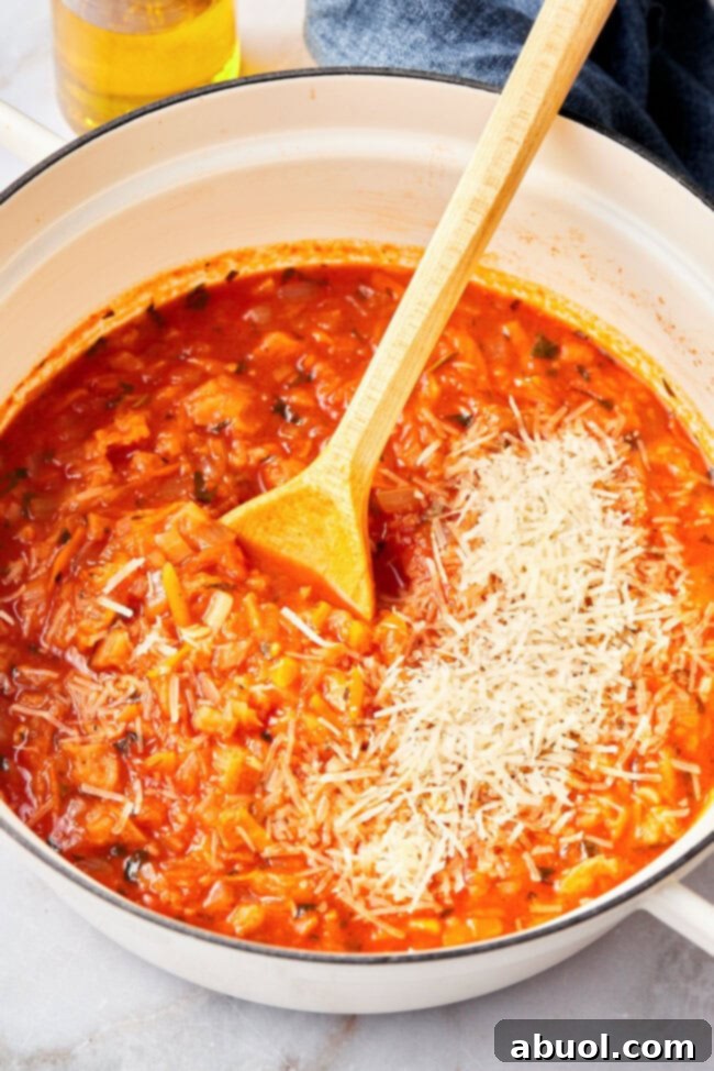 Pot of Pappa al Pomodoro simmering, with Parmesan cheese being added, creating a rich and creamy texture.
