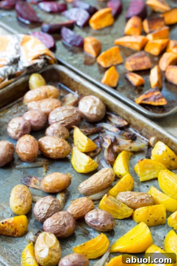 Assortment of vibrant roasted root vegetables on baking sheets, showcasing their golden-brown edges.