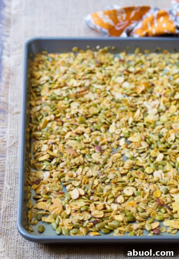 Close-up of homemade savory granola spread thinly on a baking sheet, ready for the oven.