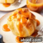 Simple baked apple recipe with puff pastry on a plate, caramel sauce over the top